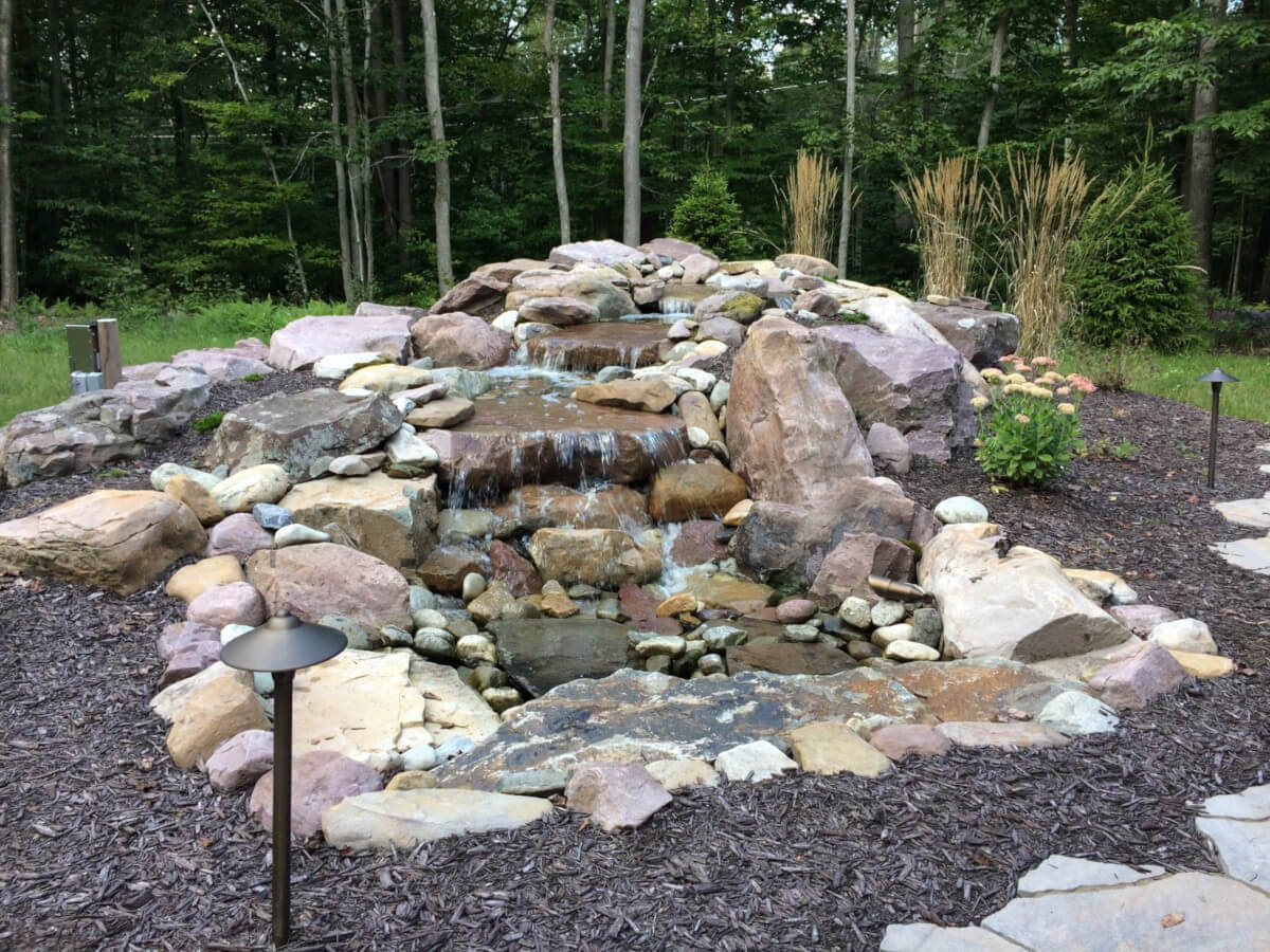 Well-maintained outdoor living space with seasonal plantings and manicured lawn by Erb's Landscaping